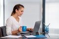 Cheerfull young business woman sitting at her desk and drinking tea. Royalty Free Stock Photo