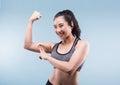 Cheerfully smiling asian sporty woman demonstrating biceps.