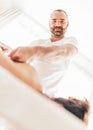 Cheerfully smiling into camera Bearded Masseur man doing massage manipulations on the Scapula area zone during young female body Royalty Free Stock Photo