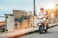 Cheerfully smiling man in helmet and sunglasses fast riding the moto scooter on the Sicilian old town streets in the Forza d`Agro