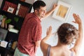 Young couple positions framed picture on the wall at home Royalty Free Stock Photo