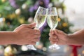 Cheerfuls Friends toasting sparkling wine. Close-ups hands of two friends toasting wine glass in the dinner party for celebrating