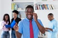 Cheering african american businessman with tie at phone with colleagues Royalty Free Stock Photo