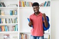 Cheering afro american male student with backpack and copy space