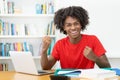 Cheering afro american male student learning at desk