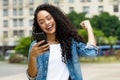 Cheering brazilian young adult woman receiving message with good news on phone Royalty Free Stock Photo