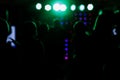 cheering crowd in front of bright blue green stage lights. Silhouette image of people dance in disco night club or Royalty Free Stock Photo