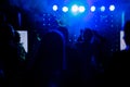 cheering crowd in front of bright blue stage lights. Silhouette image of people dance in disco night club or concert at Royalty Free Stock Photo
