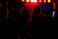 cheering crowd in front of bright red stage lights. Silhouette image of people dance in disco night club or concert at a Royalty Free Stock Photo