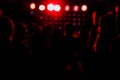 cheering crowd in front of bright red stage lights. Silhouette image of people dance in disco night club or concert at a Royalty Free Stock Photo