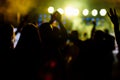 cheering crowd in front of bright yellow stage lights. Silhouette image of people dance in disco night club or concert Royalty Free Stock Photo