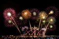 Cheering crowd watching colorful fireworks and celebrating on the beach during festival.