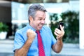 Cheering mature businessman receiving message with good news