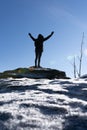 Cheering woman hiker open arms at mountain peak backlit with heavy lensflare and ice crystalls in the foreground. Royalty Free Stock Photo