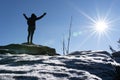 Cheering woman hiker open arms at mountain peak backlit with heavy lensflare and ice crystalls in the foreground. Royalty Free Stock Photo