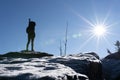 Cheering woman hiker open arms at mountain peak backlit with heavy lensflare and ice crystalls in the foreground. Royalty Free Stock Photo