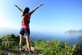 Cheering young fitness woman open arms on seaside mountain Royalty Free Stock Photo