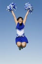 Cheerleader With Pompoms In Midair Against Sky Royalty Free Stock Photo