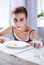 Cheerless pale woman sitting at the table