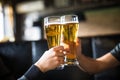 Cheers. Close-up of two men in shirts toasting with beer at the bar counter Royalty Free Stock Photo