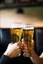 Cheers. Close-up of two men in shirts toasting with beer at the bar counter