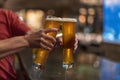 Cheersing with two cold glasses of beer