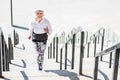 Cheery elderly lady running up concrete steps outdoors Royalty Free Stock Photo