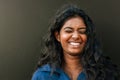Cheery indian woman laughing with eyes closed while standing over dark background