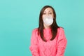 Cheery young woman in knitted pink sweater chewing blowing bubble gum balloon isolated on blue turquoise wall background Royalty Free Stock Photo