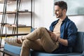 Cheery youthful bearded guy spending spare time inside apartment