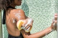Cheery youthful mulatto girl washing in shower pod