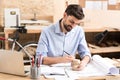 Cheery youthful woodworker doing drawings on example item in workshop