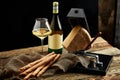 Cheese as a perfect gourmet appetizer to a glass of white wine: bread sticks, parmesan served on a wooden board, on a Royalty Free Stock Photo