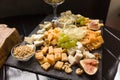 Cheese assorted or cheeseboard. Gourmet cheeses with fig, green grapes and nuts on black wooden plank. Focus on parmesan