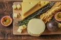 Cheese assorted cut on a wooden board with herbs and fruits.Hard and soft cheeses, rosemary and passion fruit. Mazdar Royalty Free Stock Photo