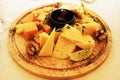 Cheese assorted on a round wooden board with a slice of lime and walnut