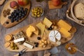 Cheese assorted on a wooden board, rustic style. Several sliced cheeses with pears, peaches, grapes, olives, honey, bread,
