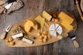 Cheese assorted on a wooden board, rustic style. Several varieties sliced cheeses: parmesan, tilsiter, halloumi with spices.
