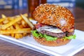 A Cheese, Bacon hamburger with french fries on a white plate Royalty Free Stock Photo