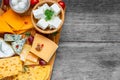 Cheese board. Assortment cheeses on wooden cutting board. Cheese plate served with grape fruits, tomatoes and rosemary Royalty Free Stock Photo