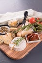 Cheese board with selection of cheeses served with olives, tomatoes and herbs at black table background Royalty Free Stock Photo