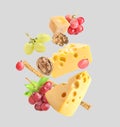 Cheese, breadstick, grapes and walnuts falling against light grey background Royalty Free Stock Photo