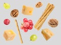 Cheese, breadsticks, grapes and walnuts falling against light grey background