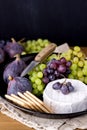 Cheese Brie Camembert with Figs and Grapes on wooden table Food for Wine Figs Green and Red Grapes Crackers Knife Plate Snacks Ver Royalty Free Stock Photo