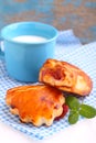 Cheese buns with cherry jam. Blue cup with milk Royalty Free Stock Photo