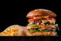 Cheese burger with grilled meat, cheese, tomato and potatoes on dark wooden surface. Ideal for advertisement. Close-up Royalty Free Stock Photo