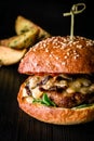 Cheese burger with grilled meat, cheese, tomato and potatoes on dark wooden surface. Ideal for advertisement. Close-up Royalty Free Stock Photo