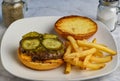 cheese burger top with pickles and relish served with fries