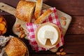 Cheese camembert or brie with bagette, nuts and dried apricots served on wooden board from above