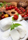 Cheese collection, eating. of white soft Italian cheese mozzarella, served with red cherry tomatoes, fresh basil leaves